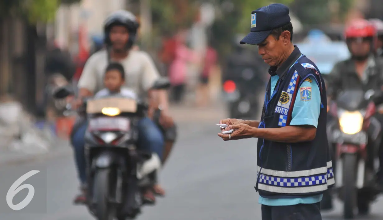 Petugas parkir mengecek struk kendaraan yang parkir di Jalan Sabang, Jakarta, Senin (21/9/2015). Sesuai janji Unit Pengelola Perparkiran Dishub mereka akan diberi gaji mencapai dua kali upah minimum provinsi (UMP). (Liputan6.com/Gempur M Surya)