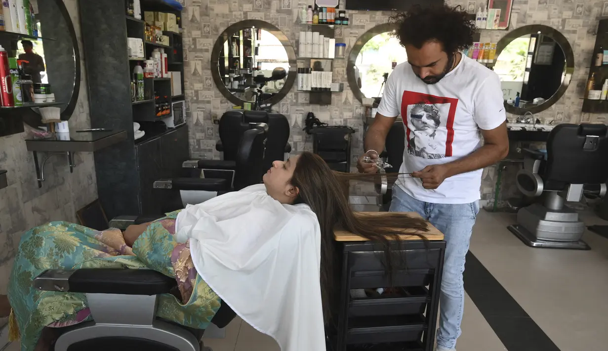 Dalam gambar pada 8 April 2021, tukang cukur Pakistan Ali Abbas menggunakan pecahan kaca untuk memotong rambut seorang pelanggan di tokonya di Lahore. Berharap membuktikan kemampuannya dalam persaingan, Ali Abbas mengandalkan berbagai alat yang tidak biasa untuk melatih keahliannya. (Arif ALI/AFP)