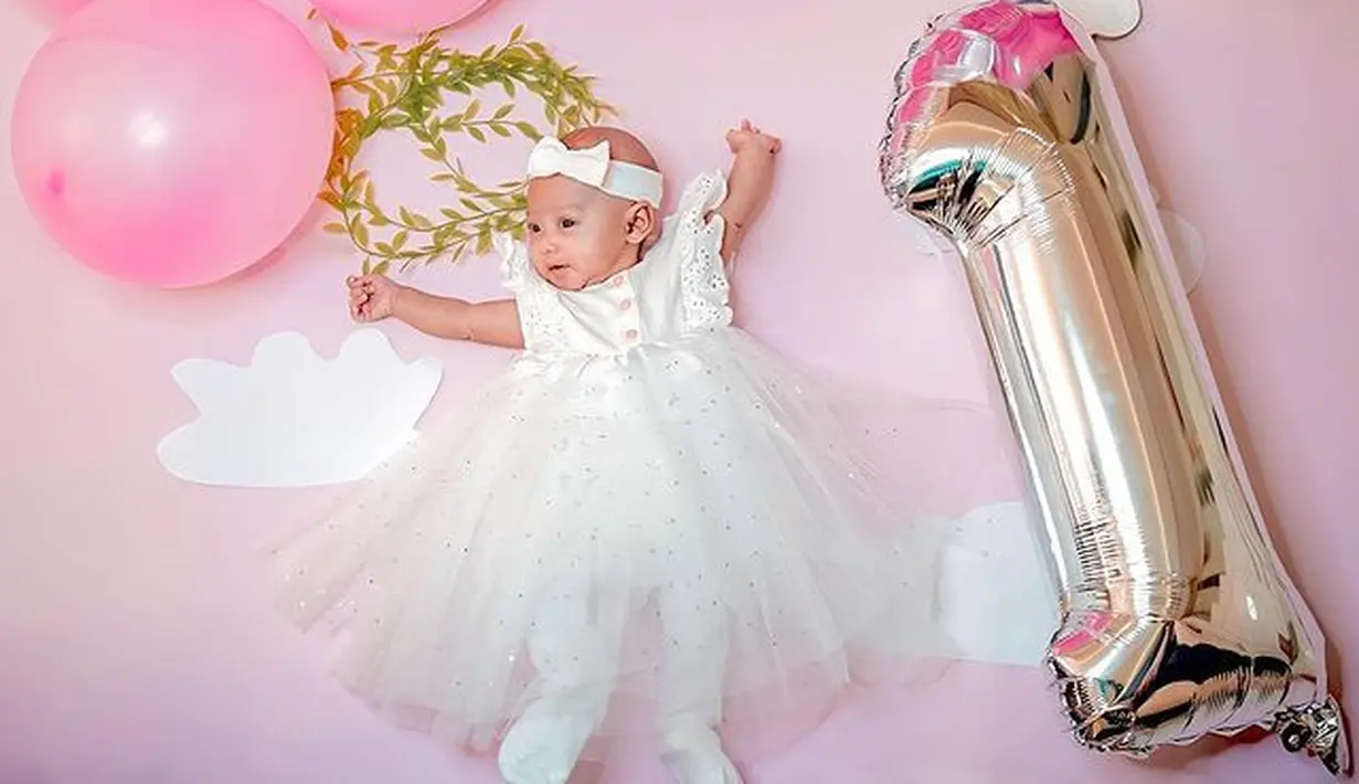 Di momen satu bulanan, Moana tampil cantik mengenakan dress putih. Dress berbahan tulle dan satin itu membuat Baby Moana tampil feminin. (instagram/riaricis1795)