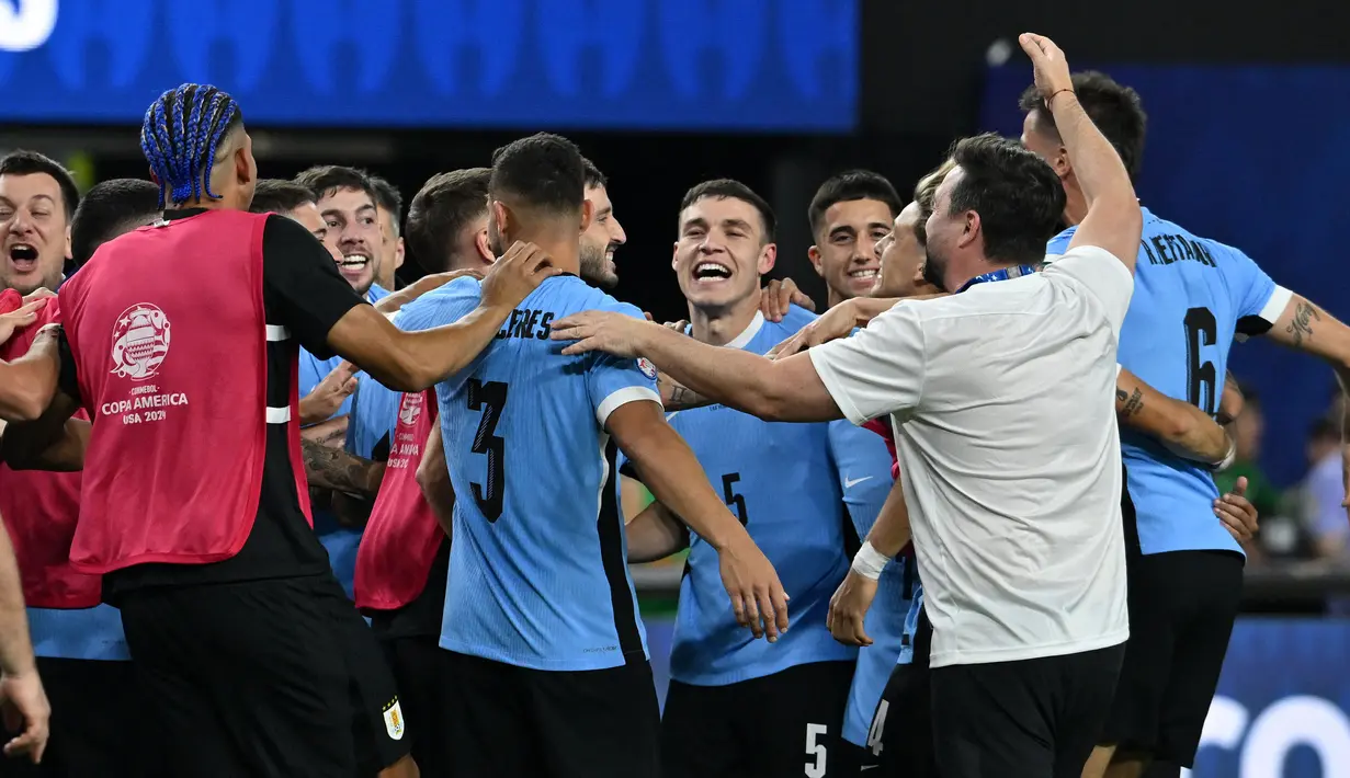Gelandang Uruguay, Manuel Ugarte (tengah) merayakan dengan rekan setimnya setelah mencetak gol dalam adu penalti untuk memenangkan pertandingan perempat final Copa America 2024 melawan Brasil di Stadion Allegiant, Las Vegas, Nevada pada 6 Juli 2024 atau Minggu 7 Juli 2024 WIB. (Robyn BECK/AFP)