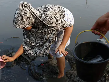 Seorang ibu bersama anaknya mencari ikan dan udang di bantaran Kanal Banjir Timur, Cipinang Muara, Jakarta, Selasa (16/5). Kegiatan itu dilakukan sejumlah ibu bersama anak-anaknya untuk mengisi masa libur sekolah. (Liputan6.com/Immanuel Antonius)