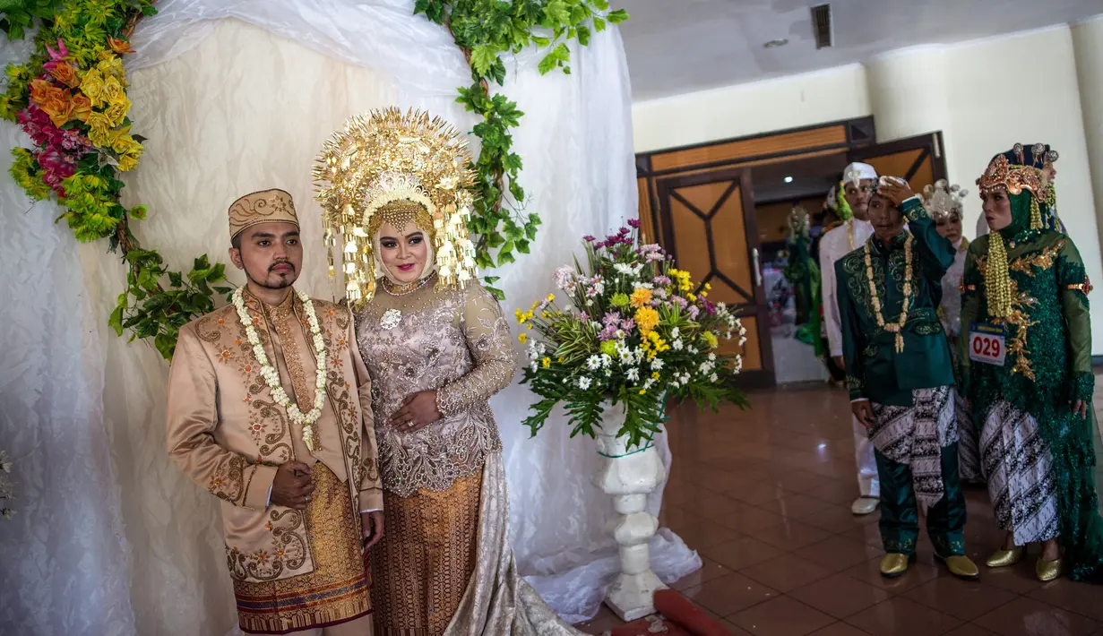 Sejumlah pasangan pengantin antre untuk foto saat mengikuti nikah massal di Surabaya, Jawa Timur, Rabu (18/12/2019). Sebanyak 60 pasangan pengantin mengikuti nikah massal yang digelar Dinas Sosial Kota Surabaya. (JUNI KRISWANTO/AFP)