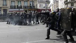 Polisi anti huru hara Prancis melemparkan tabung gas air mata ke arah pengunjuk rasa perayaan May Day di Paris, Senin (1/5). Seorang perwira polisi Prancis mengalami luka bakar dan dua lainnya luka-luka dalam bentrokan tersebut. (Zakaria ABDELKAFI/AFP)