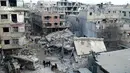 Orang-orang berkumpul di antara bangunan yang hancur saat serangan udara pasukan pemerintah Suriah di Ghouta, pinggiran kota Damaskus, Suriah, Kamis (22/2). (Ghouta Media Center via AP)