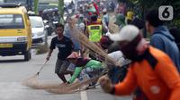 Sejumlah warga berebut sedekah pemberian pengendara kendaraan bermotor di kawasan Jembatan Sewo, Indramayu, Jawa Barat, Jumat (29/4/2022). Aksi mengambil uang sedekah menggunakan sapu meningkat saat puncak arus mudik. (Liputan6.com/Herman Zakharia)