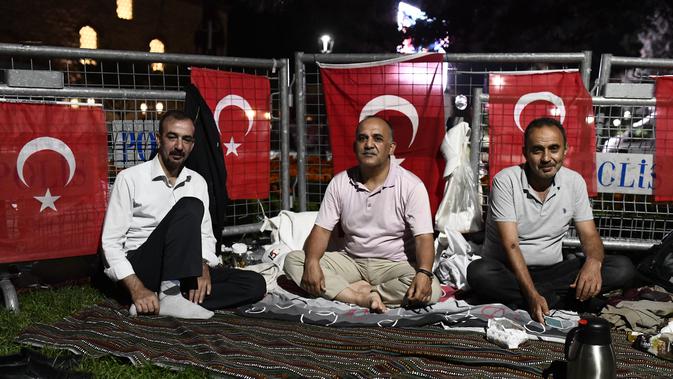 Orang-orang duduk di luar Hagia Sophia era Bizantium, di distrik bersejarah Sultanahmet di Istanbul, Kamis, 23 Juli 2020, sehari sebelum sholat Muslim pertama di monumen tengara dalam 86 tahun setelah konversi kembali menjadi masjid. (AP Photo/Omer Kuscu)