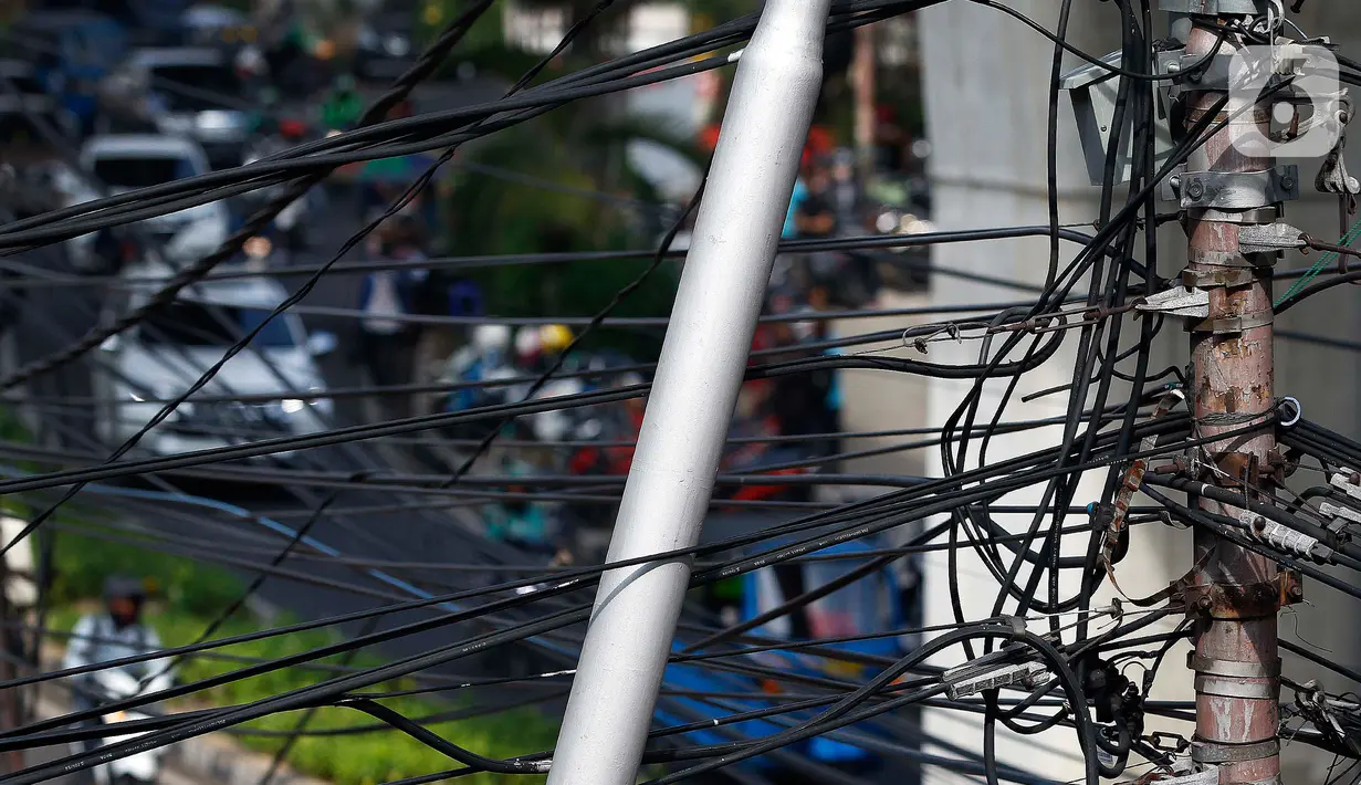 Kabel listrik dan kabel optik yang terlihat semrawut di kawasan Taman Puring, Jakarta, Jumat (3/7/2020). Kesemrawutan kabel ini sering terlihat di sejumlah kawasan Jakarta yang menyebabkan keindahan menjadi hilang dan pemandangan kurang enak untuk dilihat. (Liputan6.com/Johan Tallo)