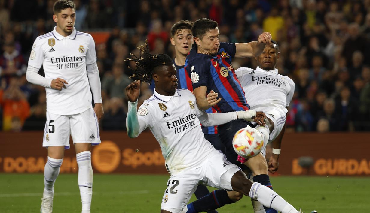 Striker Barcelona, Robert Lewandowski (tengah) diadang dua pemain Real Madrid, Eduardo Camavinga (kiri) dan David Alaba pada laga leg kedua semifinal Copa del Rey 2022/2023 di Camp Nou Stadium, Barcelona, Kamis (6/4/2023) dini hari WIB. (AP Photo/Joan Monfort)