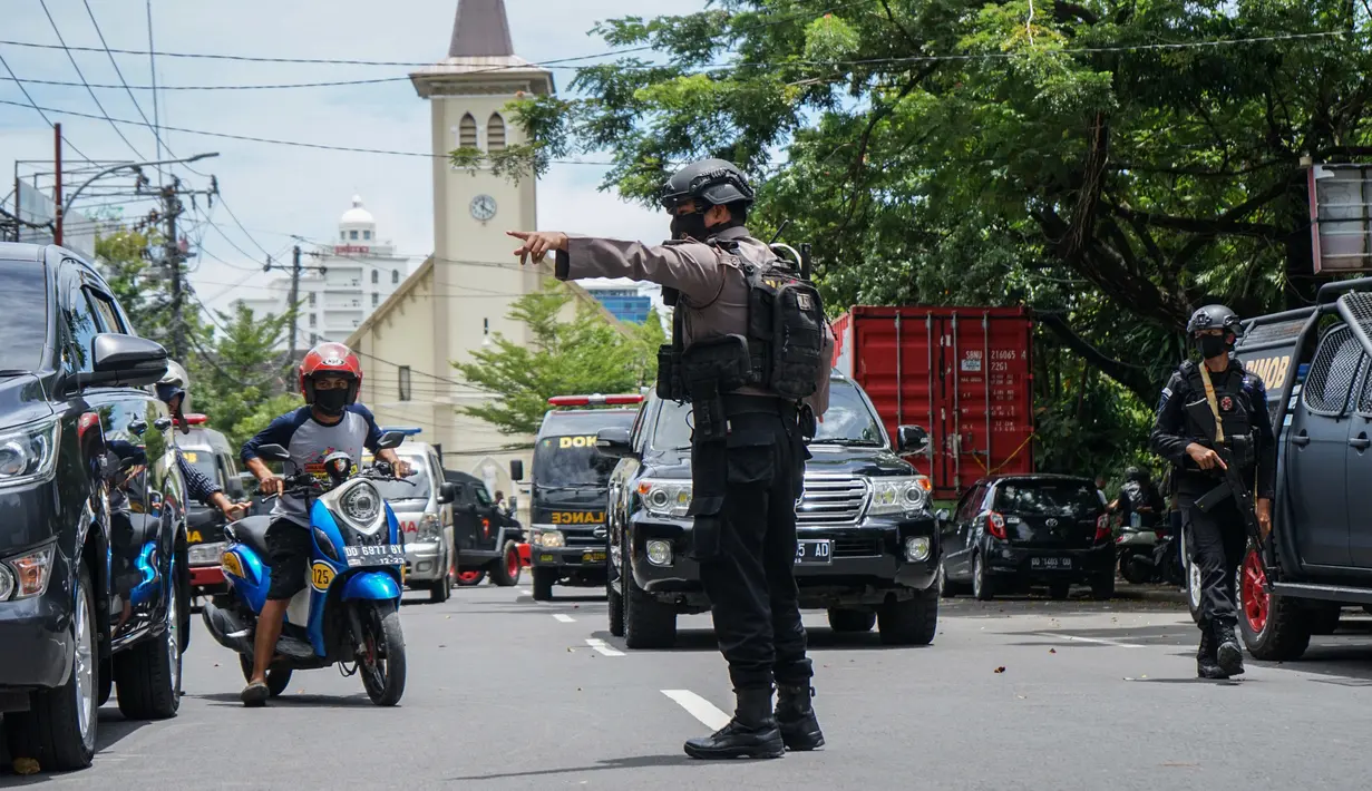 Seorang polisi mengatur lalu lintas setelah ledakan di luar sebuah gereja di Makassar (28/3/2021). Pernyataan itu disampaikan setelah Tim Labfor melakukan olah Tempat Kejadian Perkara (TKP). Kepolisian menemukan jasad tepat di samping sepeda motor yang terjatuh. (AFP/Daeng Mansur)