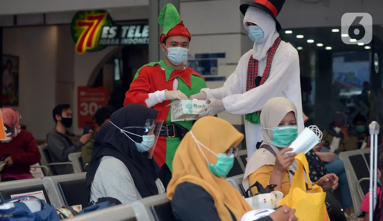 Petugas KAI yang mengenakan kostum Natal membagikan masker kepada calon penumpang di Stasiun Senen, Jakarta, Jumat (25/12/2020). Pembagian ini juga untuk memutus mata rantai penyebaran COVID-19 saat mudik Natal dan Tahun Baru 2021. (merdeka.com/Imam Buhori)