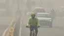 Seorang pengendara sepeda mengenakan masker menembus kabut asap pekat yang menyelimuti jalan di New Delhi, Selasa (12/11/2019). Kabut asap kembali menyelimuti ibu kota India setelah akhir pekan dengan udara cerah dan cuaca yang lebih baik. (Photo by Money SHARMA / AFP)