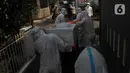 Petugas pemulasaraan jenazah Covid-19 membawa peti jenazah yang meninggal ketika menjalani isolasi mandiri di Kampung Gedong, Jakarta, Sabtu (10/7/2021). Proses pemulasaran jenazah dilakukan sesuai prokes Covid-19 dikarenakan hasil test swab korban positif. (merdeka.com/Imam Buhori)