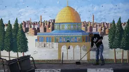 Pria Palestina menyapu jalan di Hebron di Tepi Barat yang diduduki Israel (7/12). Otoritas Palestina menyerukan demonstrasi di kota Ramallah di Tepi Barat menyusul keputusan Donald Trump mengakui Yerusalem sebagai ibu kota Israel. (AFP Photo/Hazem Bader)