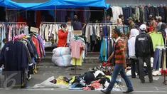 Pedagang menjajakan pakaian bekas di kawasan Pasar Senen, Jakarta, Senin (23/1). Pascakebakaran beberapa hari lalu, para pedagang terpaksa berjualan di luar gedung, meskipun menutup jalan dan mengganggu arus lalu lintas. (Liputan6.com/Immanuel Antonius)