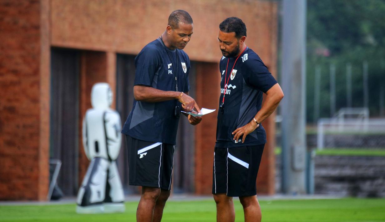 Pelatih kepala Timnas Indonesia, Patrick Kluivert (kiri) berdiskusi dengan asisten pelatih Denny Landzaat saat melakukan latihan persiapan menjelang laga Ronde 3 Kualifikasi Piala Dunia 2026 melawan China di Bali United Training Center, Bali, pada Selasa sore (23/05/2025). (Bola.com/Alit Binawan)