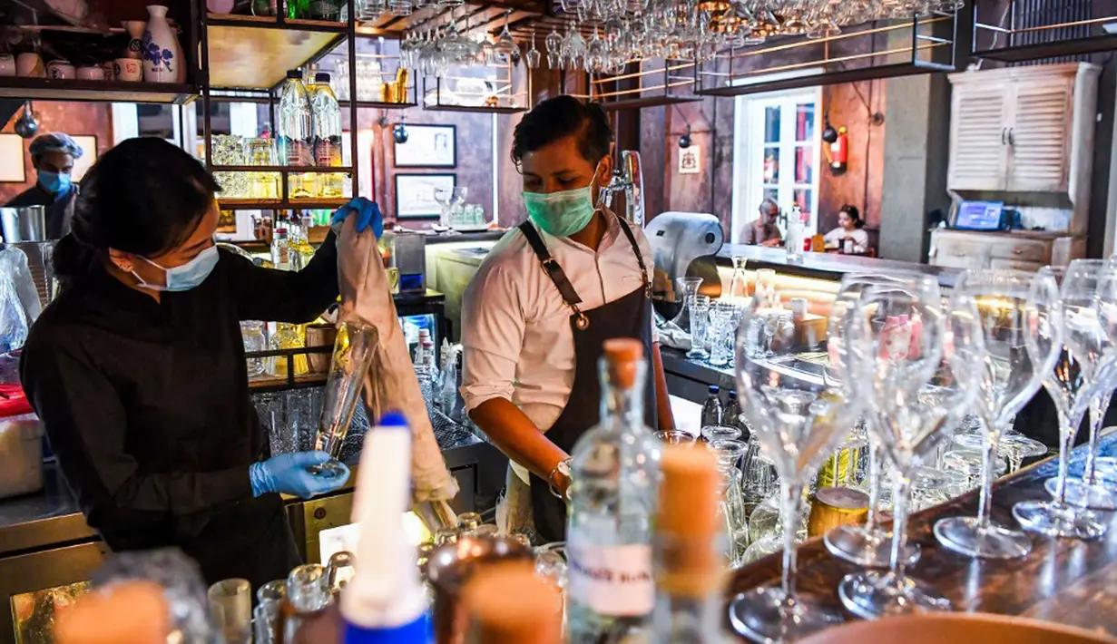 Bartender Gagan (kanan) dan seorang pelayan membersihkan bar jelang pembukaan kembali di New Delhi, 8 September 2020. Setelah sebelumnya ditutup karena pandemi COVID-19, mulai 9 September 2020 New Delhi mengizinkan bar kembali buka dengan kapasitas tempat duduk 50 persen. (Prakash SINGH/AFP)