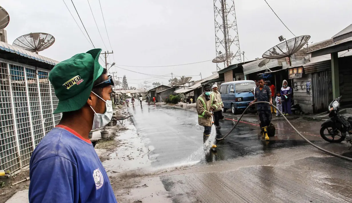 Petugas membersihkan jalanan yang tertutup abu vulkanik Gunung Sinabung di Karo, Sumatra Utara (19/2). Gunung Sinabung kembali aktif pada tahun 2010 untuk pertama kalinya sejak 400 tahun terakhir. (AFP Photo/Ivan Damanik)