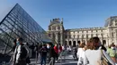 Pengunjung mengentre di piramida Louvre yang dirancang arsitek China Ieoh Ming Pei, pintu masuk ke Museum Louvre pada hari pertama pembukaan di Paris (6/7/2020). Setelah berbulan-bulan ditutup akibat lockdown Covid-19, Museum Louvre  kembali dibuka pada 6 Juli 2020. (AFP/Francois Guillot)