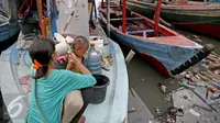 Seorang ibu memandikan anaknya di atas kapal pasca penggusuran permukiman Pasar Ikan, Jakarta, Selasa (13/4). Warga Pasar Ikan mengaku belum mendapat rumah susun sewa yang telah dijanjikan oleh Pemprov DKI Jakarta. (Liputan6.com/Faizal Fanani)