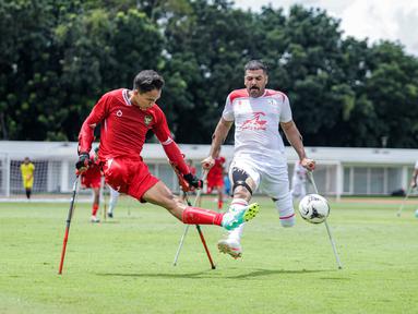 Pemain Timnas Amputasi Indonesia, Agung Rizki Satria (kiri) berusaha mengumpan bola dibayangi pemain Iran dalam laga Grup A Kualifikasi Piala Dunia Amputasi 2026 di Stadion Madya, Senayan, Jakarta, Kamis (13/11/2025). (Bola.com/Bagaskara Lazuardi)