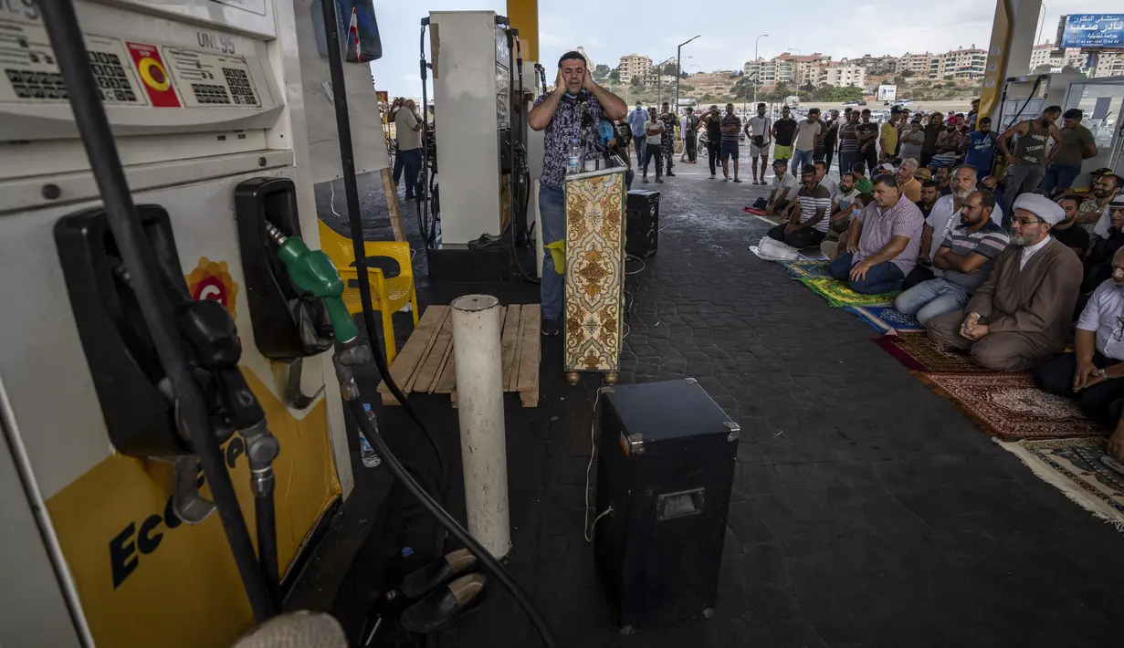Seorang pria mengumandangkan adzan ketika puluhan orang mengadakan salat Jumat di sebuah pompa bensin di kota pesisir Jiyeh, selatan Beirut, Jumat (3/9/2021). Sholat Jumat digelar di Pom Bensin ketika Lebanon terus bergulat dengan kekurangan bahan bakar yang menyesakkan. (AP Photo/ Hassan Ammar)