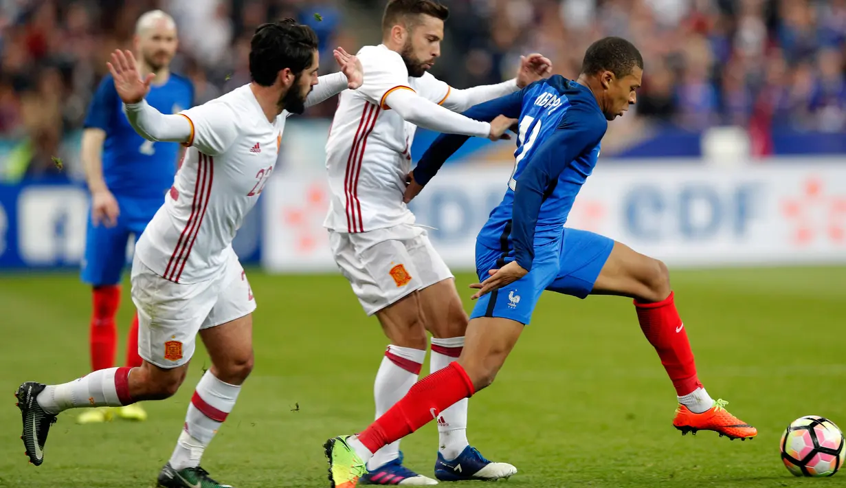 Penyerang Prancis, Kylian Mbappe (kanan) berusaha membawa bola dari kejaran dua pemain Spanyol Isco dan Jordi Alba pada laga persahabatan di Paris, (29/3). Spanyol menang atas Prancis dengan skor 2-0. (AP Photo / Christophe Ena)