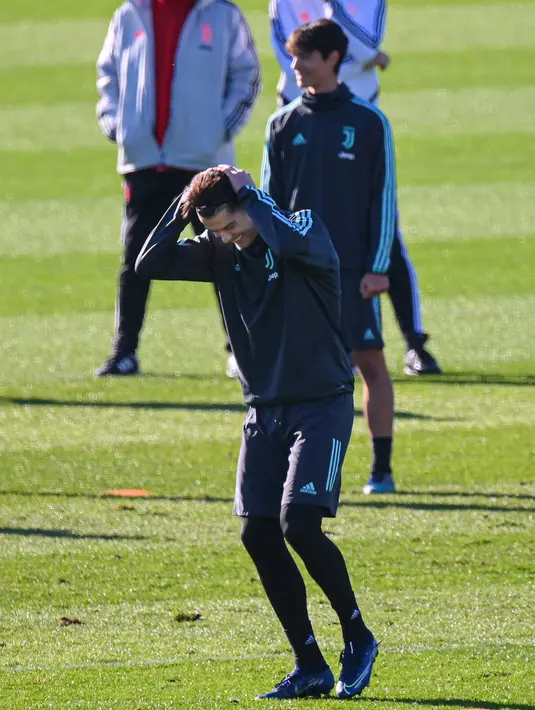 Penyerang Juventus, Cristiano Ronaldo (depan) tertawa saat merapikan rambutnya selama mengikuti sesi latihan tim di Turin, Italia (10/12/2019). Juventus akan bertanding melawan wakil Jerman, Bayern Leverkusen pada Grup D Liga Champions di BayArena. (AFP/Marco Bertorello)