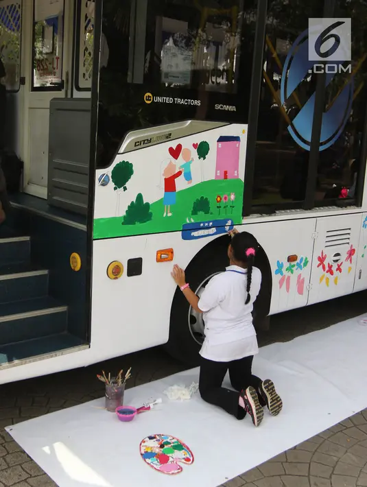 Seorang anak berkebutuhan khusus melukis bus Transjakarta di halaman Balai Kota, Jakarta, Jumat (20/4). Kegiatan tersebut dalam rangka memperingati Hari Kartini. Tema lukisan yang diangkat adalah ‘Ibuku Perempuan Tangguh’. (Liputan6.com/Arya Manggala)