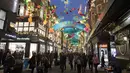 Pengunjung berjalan di bawah lampu perayaan Natal di Carnaby Street, di pusat kota London, Inggris (5/12). (AFP Photo/Justin Tallis)