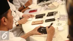 Presiden Joko Widodo menandatangani sejumlah telepon seluler milik wartawan usai berbuka puasa di Istana Negara, Jakarta, Senin (6/7/2015). Sekitar 300 wartawan menghadiri acara buka puasa bersama Jokowi tersebut. (Liputan6.com/Faizal Fanani)