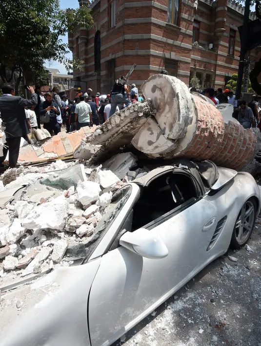 Sebuah mobil yang hancur tertimpa bangunan setelah gempa mengguncang Kota Meksiko (19/9). Gempa terjadi tepat 32 tahun sejak gempa dahsyat menewaskan ribuan orang di Mexico City pada 1985. (AFP Photo/Alfredo Estrella)