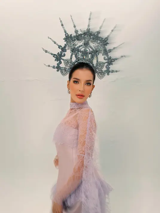 Pose menoleh ke kamera memperlihatkan makeup sculpted dengan kulit berkilau dan lipgloss coral yang segar. Crown silver berhias kristal beraneka warna dan jari-jari bermutiara berpadu dengan renda peplum lilac yang bergelombang di pinggang. [@tasyafarasya]
