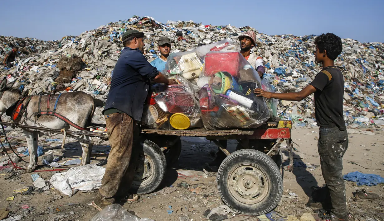 Pengumpul sampah Palestina memuat jerigen ke gerobak keledai di tempat pembuangan sampah di Kota Gaza (29/7/2019). Kemiskinan yang terjadi akibat blokade Israel dan kurangnya kesempatan kerja membuat beberapa warga Palestina memilih bekerja mencari sampah untuk dijual. (AFP Photo/Mohammed)