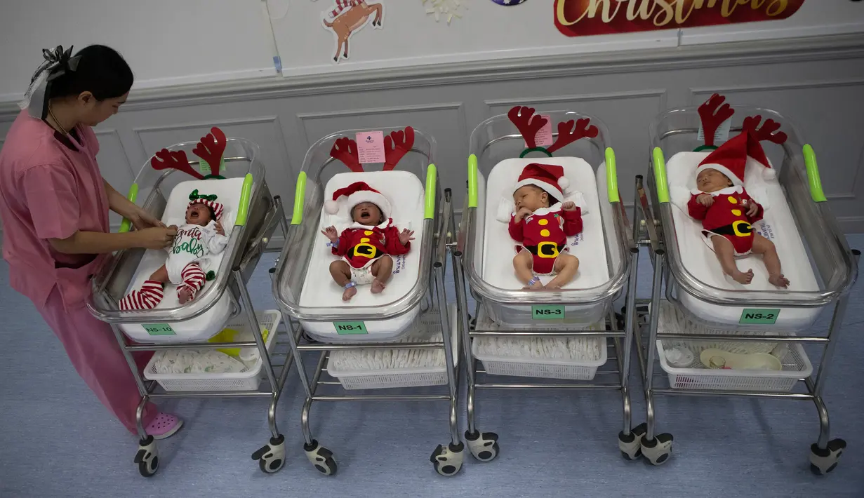 Perawat merapikan pakaian bayi yang baru lahir di Rumah Sakit Synphaet, Bangkok, Thailand, Selasa (24/12/2019). Bayi-bayi tersebut dipakaikan kostum sinterklas untuk menyambut Hari Raya Natal. (AP Photo/Sakchai Lalit)