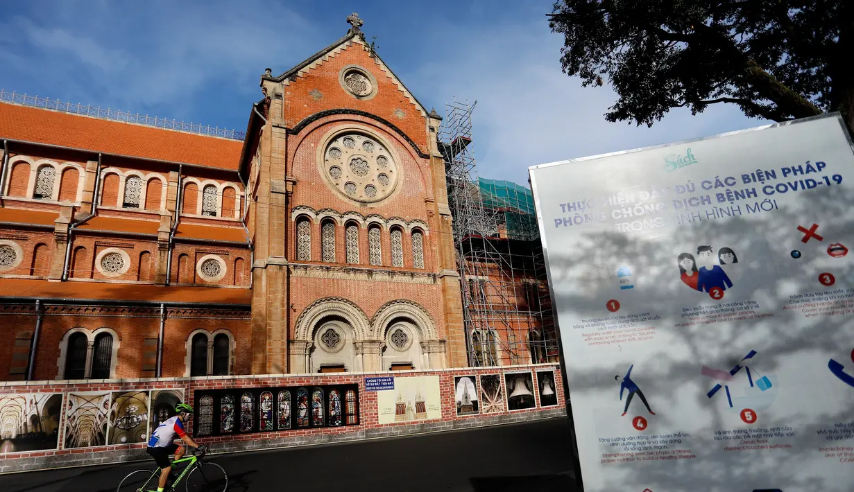 Khoa)
Seorang pria bersepeda melewati Basilika Katedral Notre-Dame Saigon pada hari pertama pemberlakuan lockdown di Kota Ho Chi Minh, Vietnam, Jumat (9/7/2021). Pemerintah Vietnam memberlakukan lockdown dua minggu di Kota Ho Chi Minh. (AFP/Huu Khoa)