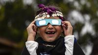Magdalena Nahuelpan, seorang gadis Adat Mapuche, melihat gerhana matahari total menggunakan kacamata khusus di Carahue, La Araucania, Chile, Senin (14/12/2020). Gerhana matahari total terlihat dari Chile dan wilayah Patagonia utara Argentina. (AP Photo/Esteban Felix)