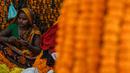 Seorang wanita membuat karangan bunga jelang Festival Diwali di pasar bunga New Delhi, India, Minggu (31/10/2021). Festival Diwali atau Festival Cahaya dalam agama Hindu melambangkan kemenangan baik atas buruk. (Money SHARMA/AFP)