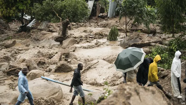 Orang-orang menyeberangi sungai yang mengamuk di Blantyre, Malawi, Senin, 13 Maret 2023.