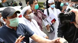 Rizieq Shihab (kedua kiri) sesaat tiba di Mapolda Metro Jaya, Jakarta, Sabtu (12/12/2020). Rizieq Shihab akan menjalani pemeriksan sebagai tersangka penghasutan dan kerumunan di tengah pandemi Covid-19. (Liputan6.com/Helmi Fithriansyah)