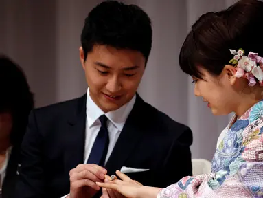 Atlet tenis meja Taiwan, Chiang Hung-chieh memasangkan cincin pernikahan ke tangan atlet tenis meja Jepang, Ai Fukuhara saat mengumumkan pernikahan kepada wartawan pada jumpa pers di Tokyo, Jepang, (21/9). (REUTERS/Toru Hanai)