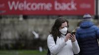 Seorang wanita mengenakan topeng untuk melindungi diri dari virus corona melihat ponselnya di Trafalgar Square, di London, Selasa (28/12/2021). Javid menuturkan, varian Omicron saat ini menyumbang sekitar 90 persen kasus baru di seluruh Inggris. (AP Photo/Alastair Grant)