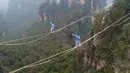 Dua kontestan berpakaian karakter Avatar berpacu sepanjang slackline di Pegunungan Huangshizhai di Zhangjiajie, Hunan, China, Minggu (23/12). Slackline merupakan olahraga keseimbangan di atas tali webbing (tali berbentuk pita). (STR/AFP)