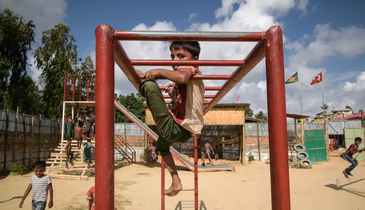 Anak-anak pengungsi Rohingya bergelantungan di tiang besi saat bermain di taman bermain kamp pengungsi Thangkhali, dekat Cox's Bazar, Bangladesh, Kamis (9/8). (Ed JONES/AFP)