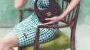Dengan versi suede, Gigi Hadid kenakan mini dress kotak-kotak hijau yang pamerkan leher jenjangnya [Miu Miu]