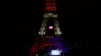 Pengunjung memandangi Menara Eiffel yang disoroti lampu pelangi, Paris, Senin (13/6/2016). Menara yang terkenal dengan romantisme itu memberikan penghormatan untuk korban penembakan brutal di klub malam gay di Orlando, Florida AS. (Thomas SAMSON/AFP)