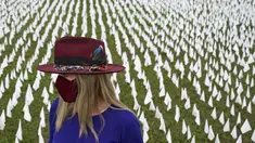 Seniman Suzanne Brennan Firstenberg berdiri di antara ribuan bendera putih yang ditanam untuk mengenang warga Amerika yang meninggal karena COVID-19 di dekat Stadion RFK di Washington, Selasa (27/10/2020). Instalasi seni publik ini disebut "In America, How Could This Happen.” (AP/Patrick Semansky)