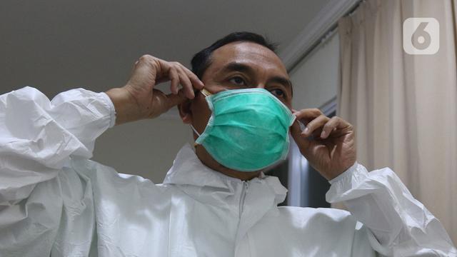 <span>dr Rahmadi Iwan Guntoro, Sp.P melapisi masker N95 dengan masker bedah di Rumah Sakit Haji, Jakarta, Kamis (9/4/2020). Gugus Tugas Percepatan Penanganan COVID-19 telah mengeluarkan rekomendasi standar APD berdasarkan tiga tingkatan perlindungan. (Liputan6.com/Herman Zakharia)</span>