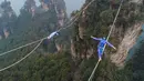 Dua kontestan berpakaian karakter Avatar berpacu sepanjang slackline di Pegunungan Huangshizhai di Zhangjiajie, Hunan, China, Minggu (23/12). Lanskap pegunungan ini menjadi rujukan film Avatar yang ternyata ada di Bumi. (STR/AFP) (STR/AFP)