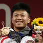 Lifter Indonesia Rahmat Erwin Abdullah merayakan di podium setelah memenangkan medali perunggu cabang angkat besi 73 kg putra Olimpiade Tokyo 2020 di Tokyo, Jepang, Rabu (28/7/2021). Rahmat Erwin Abdullah berhasil menyumbang medali perunggu untuk Indonesia. (AP Photo/Luca Bruno)