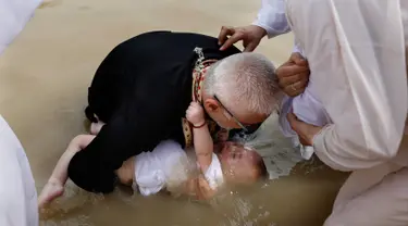 Imam Kristen Ortodoks Serbia membaptis seorang bayi di perairan Sungai Yordan di dekat kota Jericho (4/3). Di tempat ini diyakini Yesus Kristus dibaptis oleh Yohanes Pembaptis. (AFP Photo/Gali Tibbon)